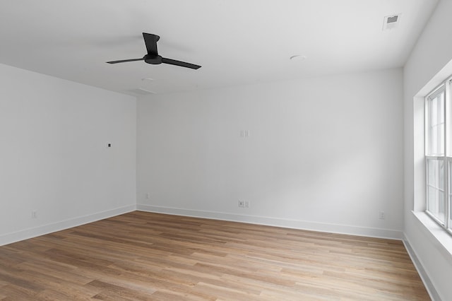 empty room with baseboards, ceiling fan, visible vents, and light wood finished floors