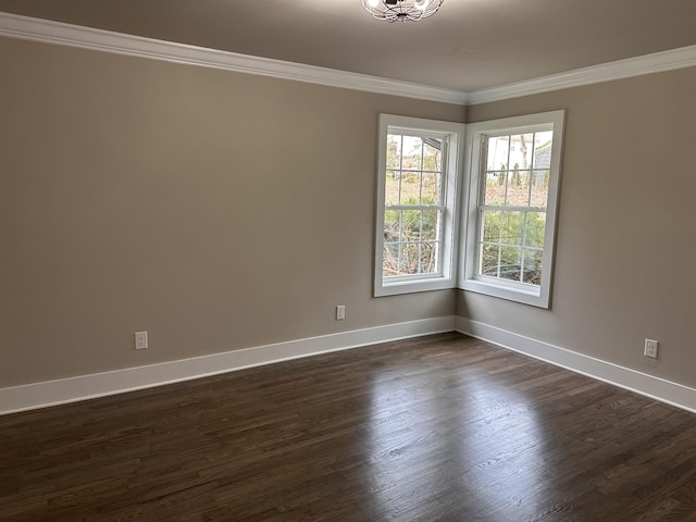 empty room with dark wood finished floors, crown molding, and baseboards