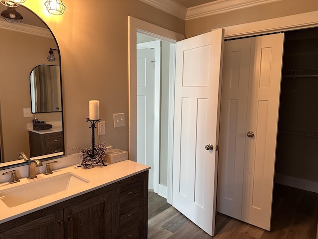 bathroom with a closet, wood finished floors, ornamental molding, and vanity
