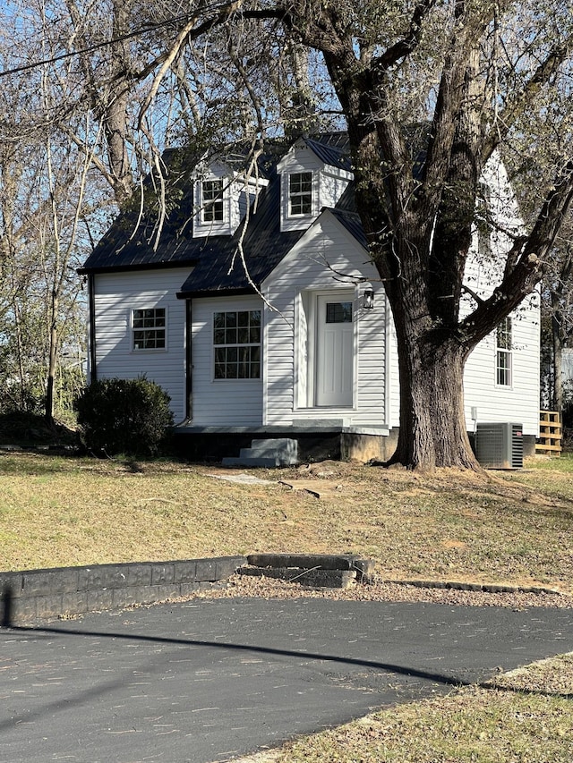 new england style home with central AC unit and a front lawn