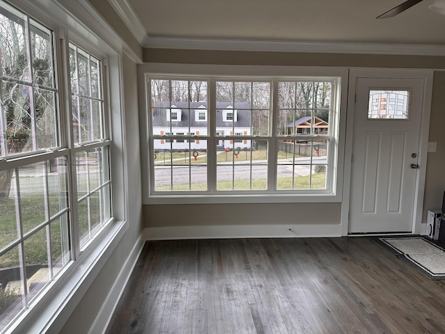 interior space featuring crown molding, a healthy amount of sunlight, and dark wood-style flooring