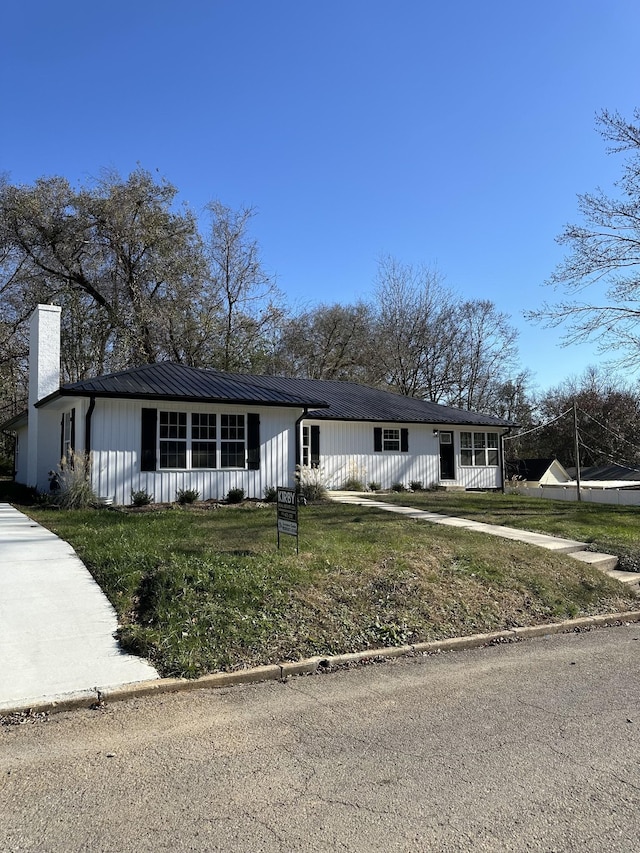 view of front of house featuring a chimney and a front yard