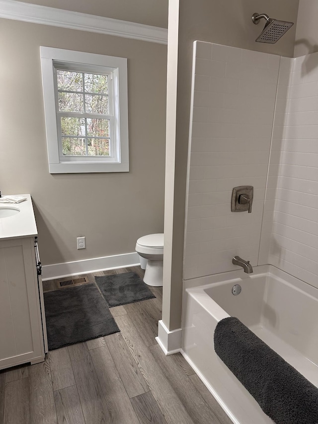 bathroom with baseboards, toilet, ornamental molding, wood finished floors, and vanity