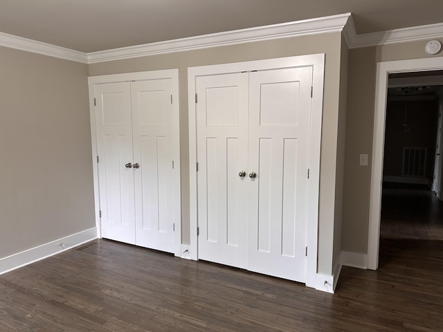 unfurnished bedroom with dark wood-type flooring, baseboards, visible vents, and ornamental molding