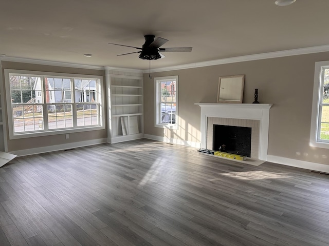 unfurnished living room featuring wood finished floors, visible vents, ceiling fan, crown molding, and a brick fireplace