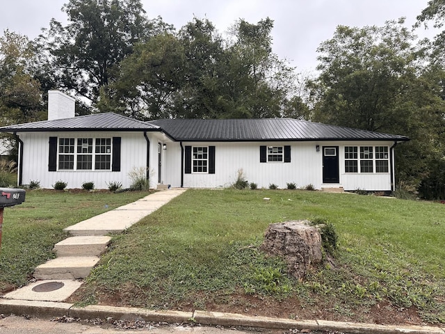 ranch-style home featuring metal roof, a front lawn, and a chimney