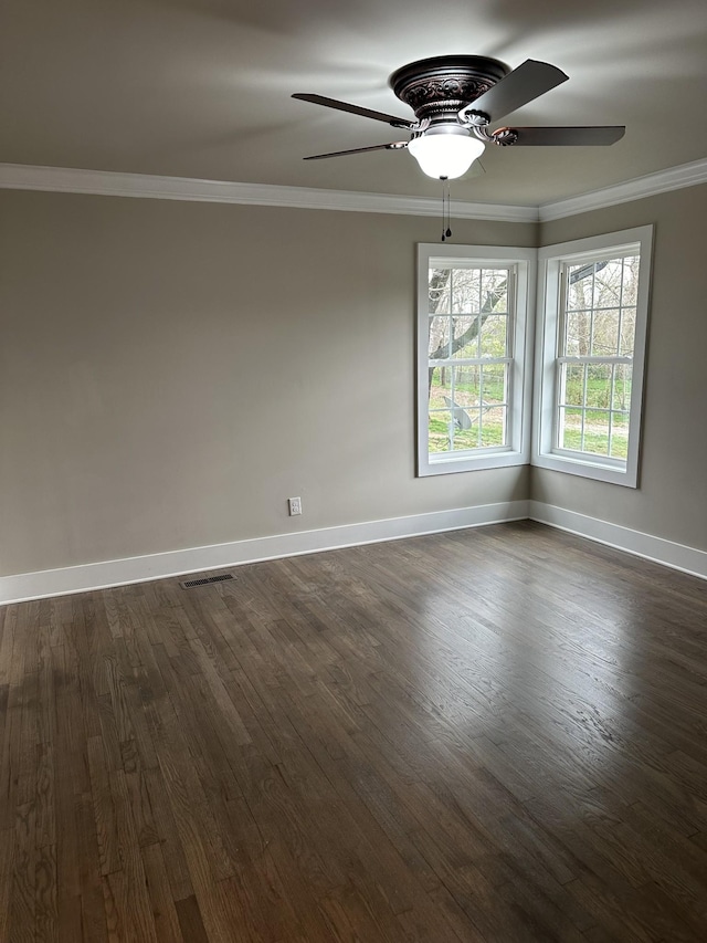 spare room with visible vents, dark wood-type flooring, ceiling fan, crown molding, and baseboards