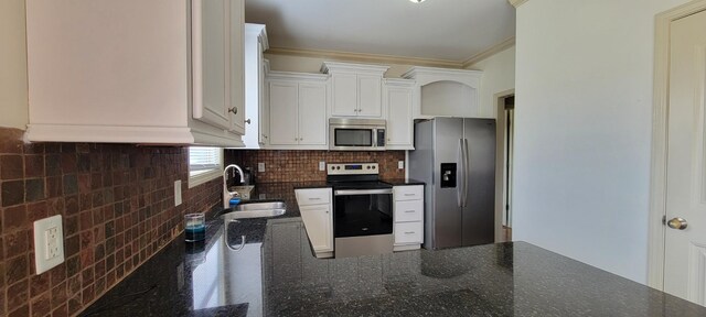 kitchen featuring decorative backsplash, stainless steel appliances, crown molding, white cabinetry, and a sink