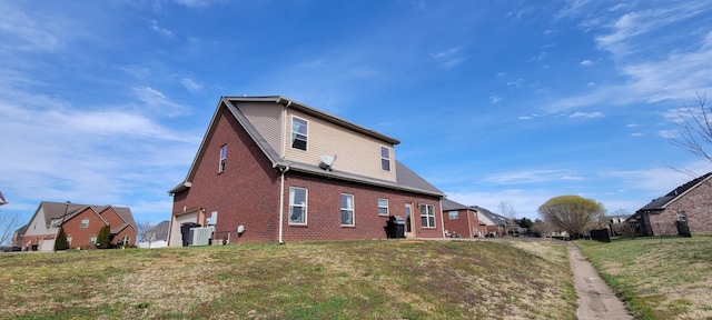 view of side of home with a garage, brick siding, and a yard