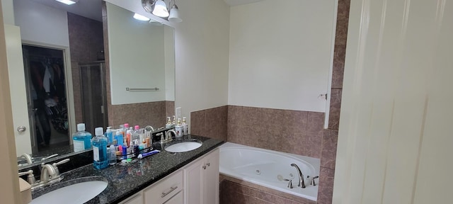 bathroom with a stall shower, a sink, a tub with jets, and double vanity