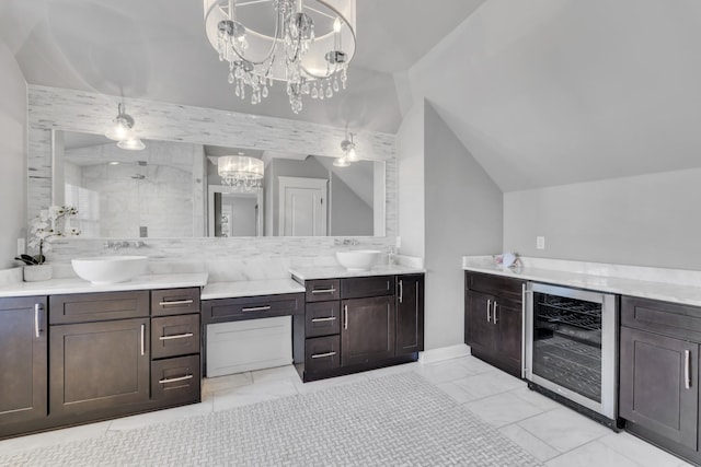 bathroom with wine cooler, marble finish floor, an inviting chandelier, vaulted ceiling, and vanity