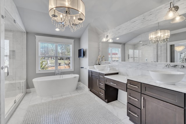 bathroom featuring double vanity, a stall shower, a chandelier, and a sink