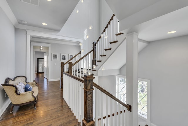 stairs featuring baseboards, visible vents, a towering ceiling, wood finished floors, and recessed lighting