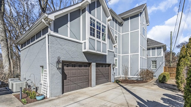 view of side of home with driveway, brick siding, an attached garage, and central air condition unit