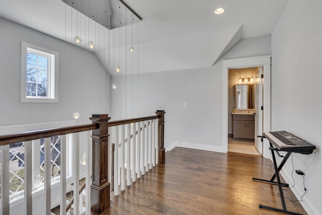 hallway with recessed lighting, vaulted ceiling, an upstairs landing, wood finished floors, and baseboards