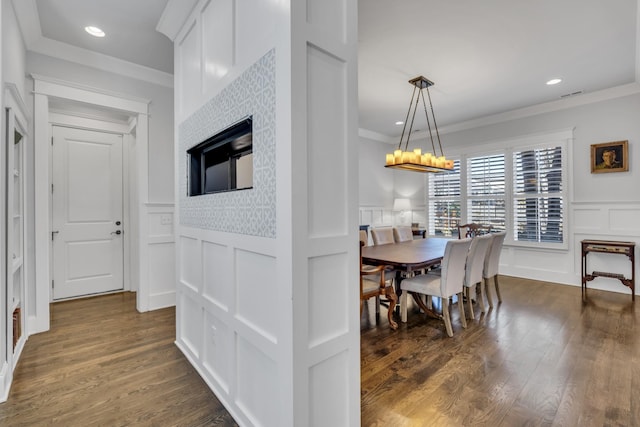 dining space with dark wood-style flooring, a decorative wall, crown molding, and recessed lighting