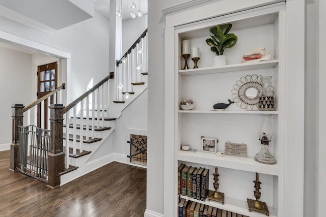 staircase featuring built in shelves, baseboards, and wood finished floors