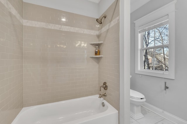 bathroom featuring marble finish floor, bathing tub / shower combination, toilet, and baseboards