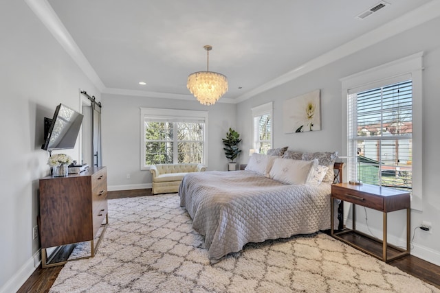 bedroom with a barn door, baseboards, visible vents, wood finished floors, and crown molding