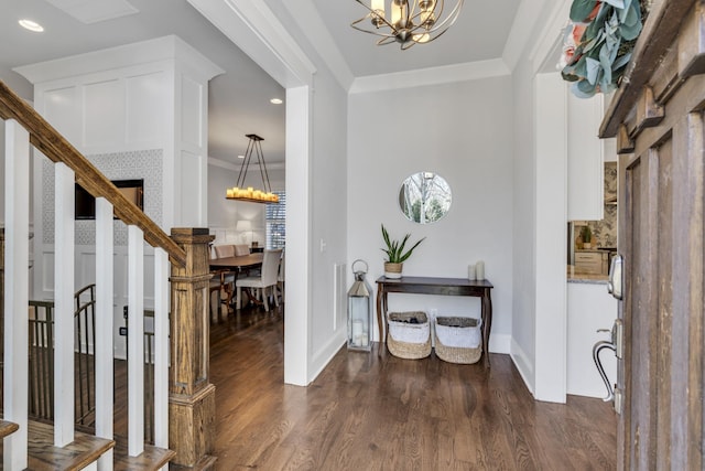 entryway featuring stairs, a chandelier, dark wood-style flooring, and ornamental molding