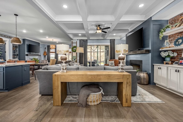 living room with ceiling fan, dark wood-type flooring, a fireplace, coffered ceiling, and beam ceiling