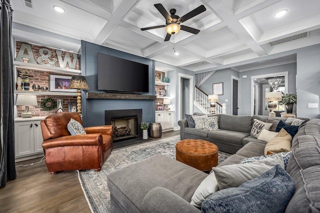 living room featuring a large fireplace, visible vents, stairs, beam ceiling, and dark wood-style floors