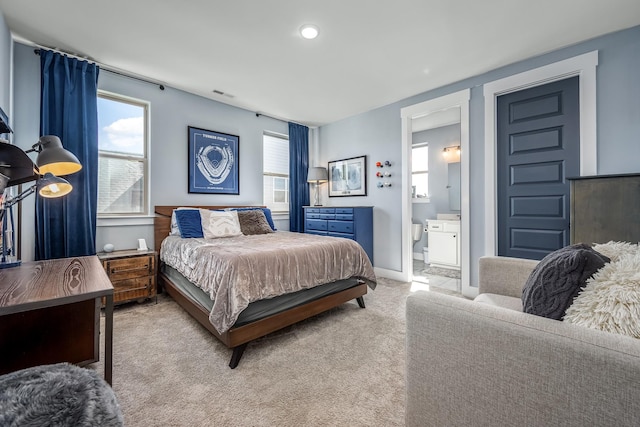 bedroom featuring light carpet, ensuite bath, visible vents, and baseboards