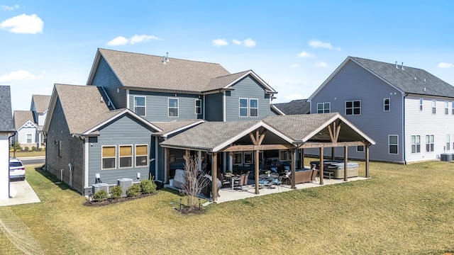 back of property featuring cooling unit, a shingled roof, a yard, a patio area, and a hot tub