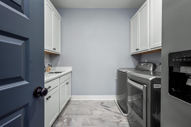 washroom featuring a sink, baseboards, marble finish floor, cabinet space, and washer and clothes dryer