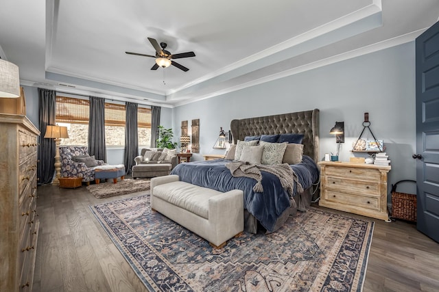 bedroom with crown molding, a tray ceiling, and dark wood finished floors