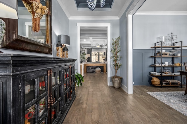 corridor featuring ornamental molding, wainscoting, a decorative wall, and wood finished floors