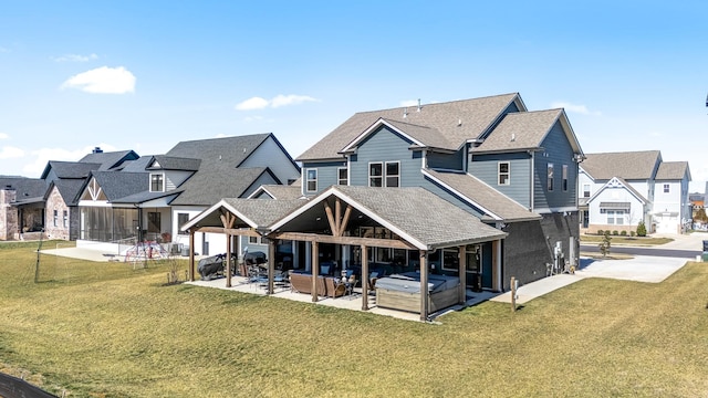 back of house featuring a yard, a residential view, a patio, and a hot tub