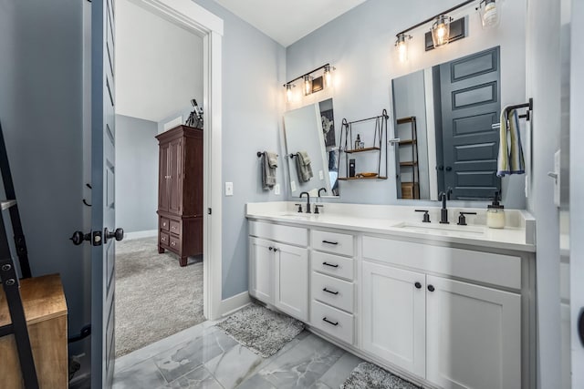 bathroom featuring double vanity, marble finish floor, baseboards, and a sink