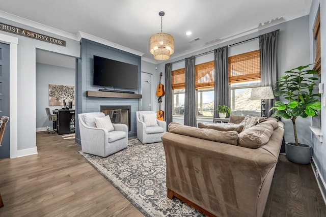 living room featuring a large fireplace, wood finished floors, visible vents, baseboards, and ornamental molding