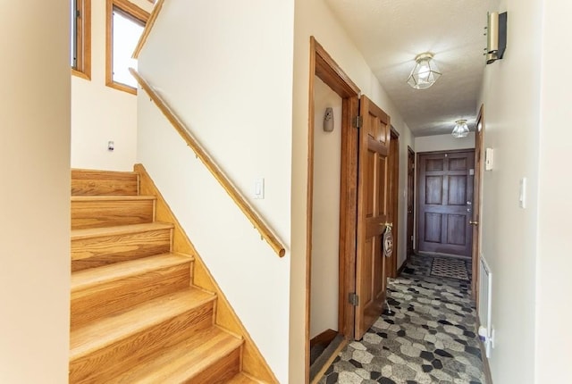 corridor with a textured ceiling, dark floors, and stairway