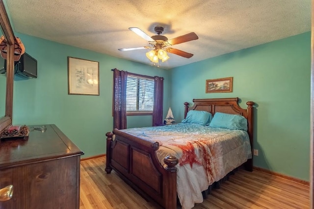 bedroom featuring a textured ceiling, ceiling fan, light wood-type flooring, and baseboards