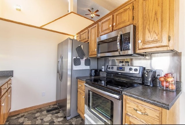 kitchen with baseboards, dark countertops, ceiling fan, appliances with stainless steel finishes, and brown cabinets