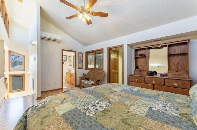 bedroom with a textured ceiling, wood finished floors, visible vents, an AC wall unit, and ensuite bath