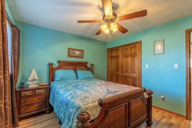 bedroom with ceiling fan, a textured ceiling, baseboards, a closet, and light wood-type flooring