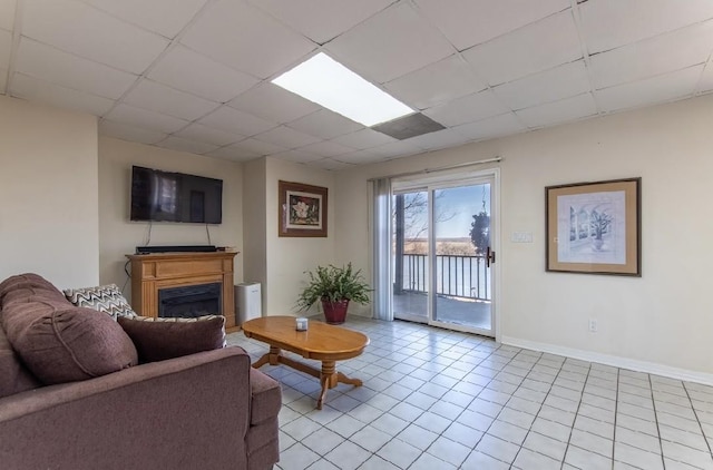 living area with a paneled ceiling, a fireplace, baseboards, and light tile patterned floors