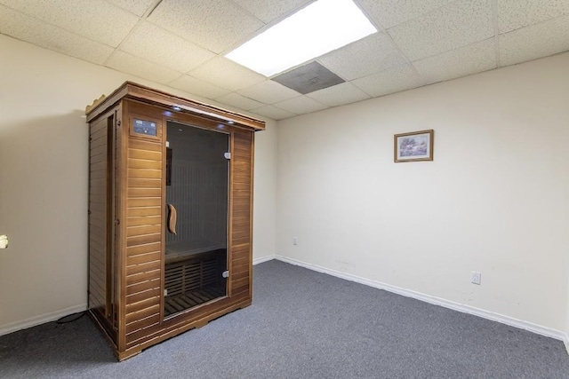 interior space featuring carpet floors, baseboards, and a drop ceiling