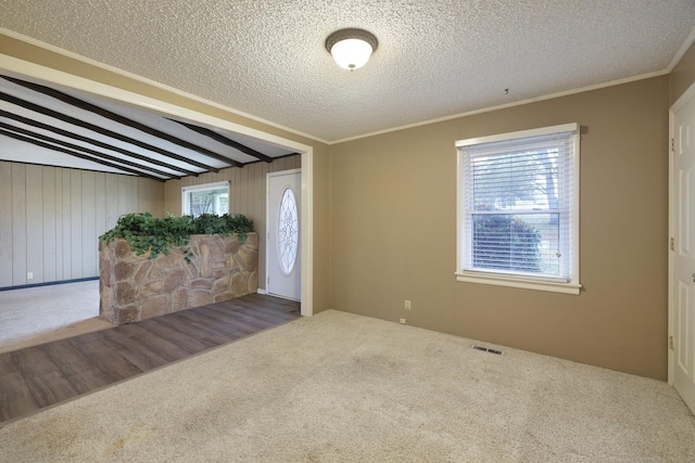 carpeted foyer entrance with a textured ceiling, ornamental molding, lofted ceiling with beams, and visible vents