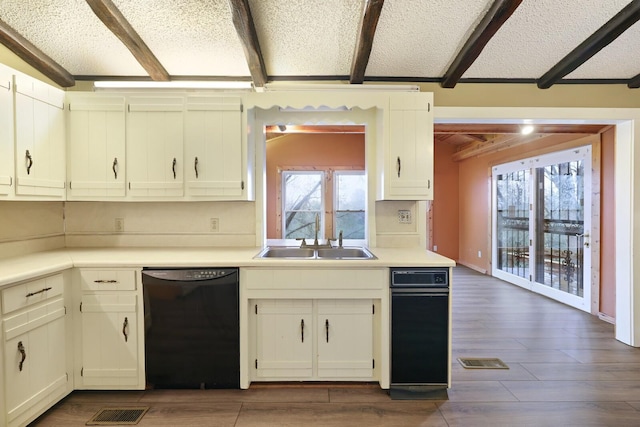 kitchen featuring dark wood finished floors, dishwasher, beam ceiling, a textured ceiling, and a sink