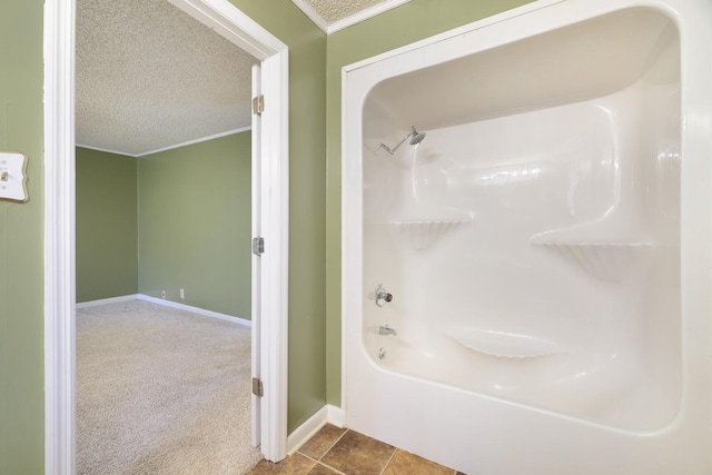 full bathroom with a textured ceiling, tile patterned flooring, baseboards,  shower combination, and ornamental molding