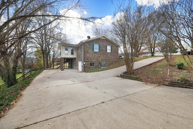 view of property exterior featuring a carport, brick siding, driveway, and central AC unit