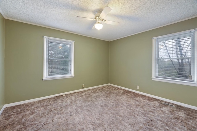 carpeted empty room with baseboards, visible vents, a ceiling fan, and ornamental molding