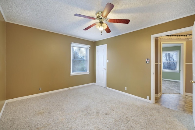 spare room with a textured ceiling, ceiling fan, baseboards, and light colored carpet