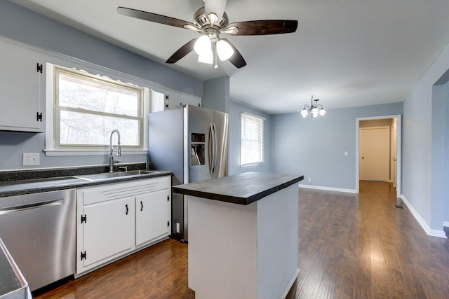 kitchen featuring stainless steel appliances, a sink, white cabinetry, dark wood-style floors, and dark countertops