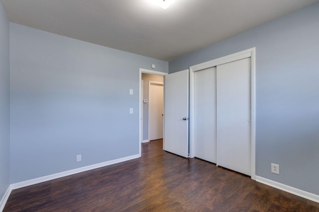 unfurnished bedroom featuring a closet, baseboards, and wood finished floors