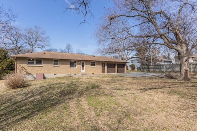 rear view of property with a garage, a lawn, crawl space, fence, and brick siding